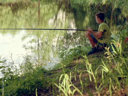 teen child catches a fishing rod on the pond.