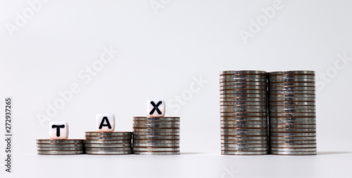 Stair-shaped coin piles and tower-shaped coin piles. A white cube with tax words. photo