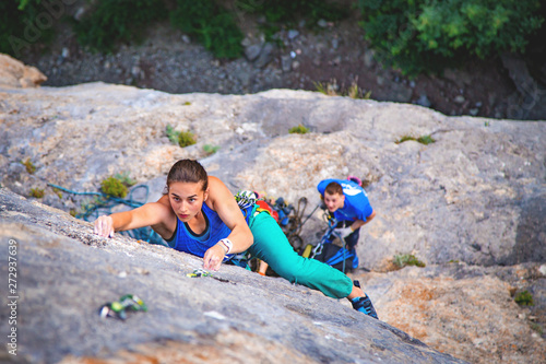 Woman climbs rock.