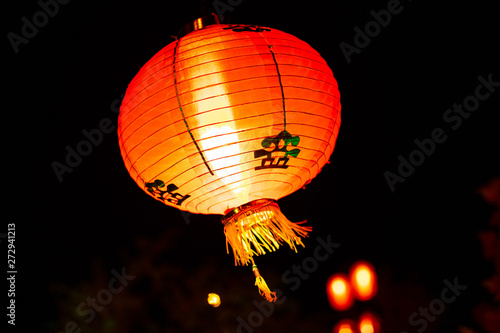 Photo of hanging chinese red lantern in the nigh. Traditional oriental red lamp.