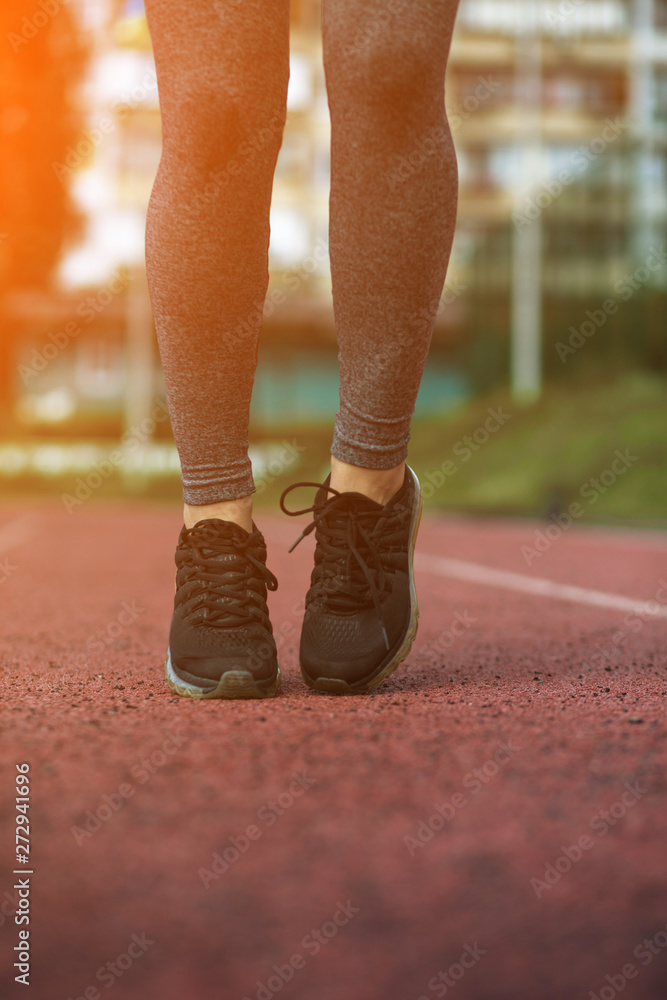 Female Legs in sneakers close-up on pink athletic track Female Legs in sneakers close-up on pink athletic track