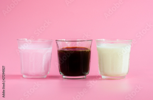 Glass of white and pink milk, black coffee on pink background. Beverage in morning concept.