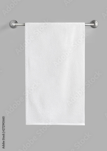 White cotton terry towel hanging on the rail isolated. White towel against the gray background. photo