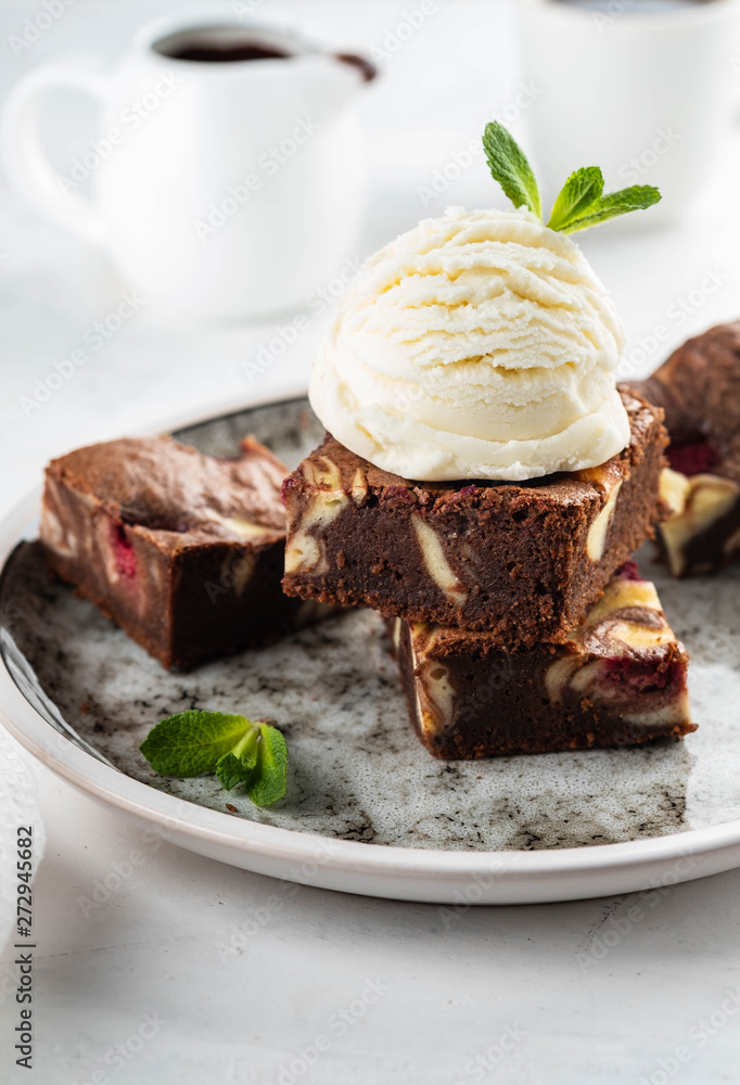 Chocolate brownie with vanilla ice cream, rasberry and mint on a white background. Copy space. Chocolate brownie with vanilla ice cream, rasberry and mint on a white background. Copy space.