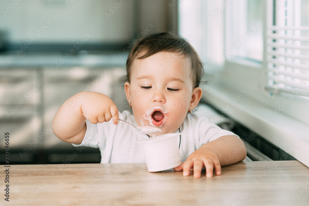 A little charming girl eats yogurt all smeared herself A little charming girl eats yogurt all smeared herself