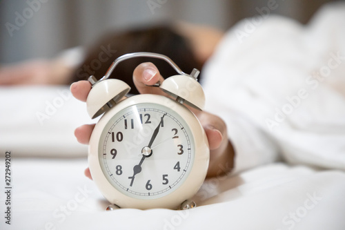 Woman pressing alarm clock in the morning
