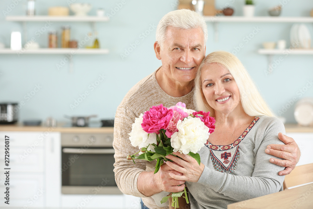 Portrait of happy mature couple with flowers in kitchen Portrait of happy mature couple with flowers in kitchen