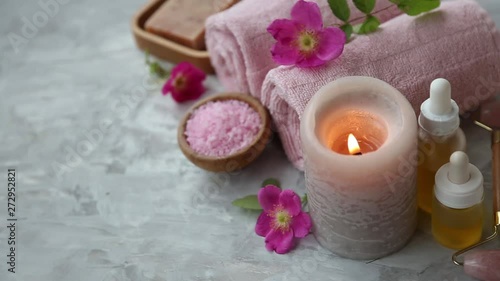 Spa candle flame burning with bath salt, flowers and oils, spa still life setting