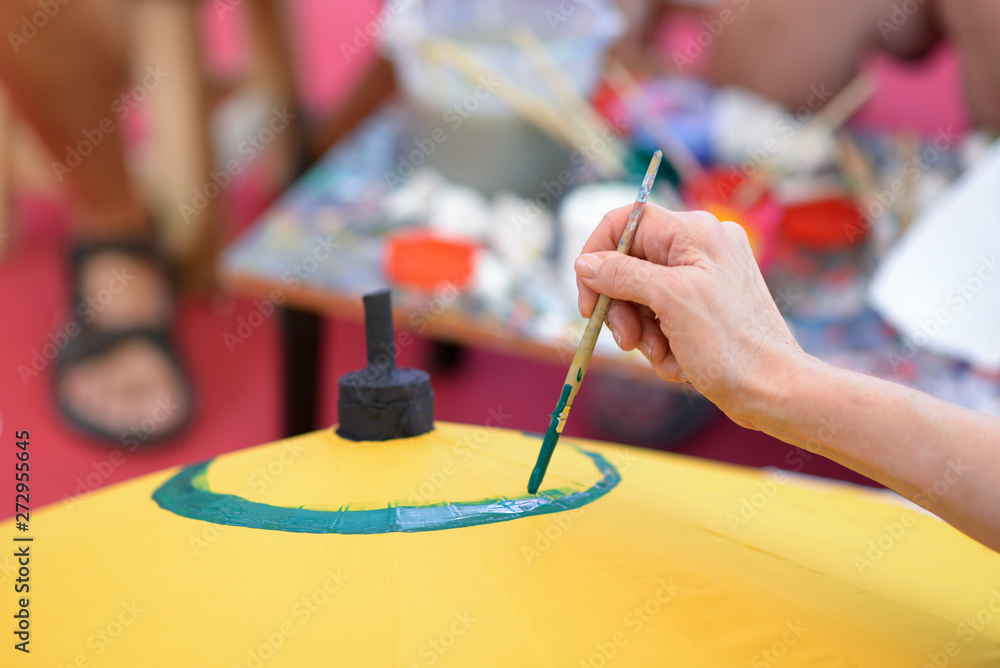Obraz premium Artist painting on Thailand's traditional umbrella.Artist drawing flowers on umbrella.Woman painting on colourful paper umbrella.Woman drawing flowers on paper umbrella.