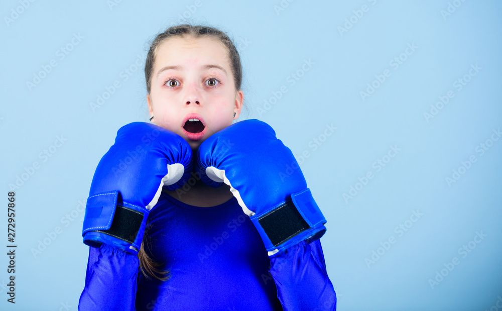 Girl cute boxer on blue background. With great power comes great responsibility. Boxer child in boxing gloves. Female boxer change attitudes within sport. Risk of injury. Rise of women boxers Girl cute boxer on blue background. With great power comes great responsibility. Boxer child in boxing gloves. Female boxer change attitudes within sport. Risk of injury. Rise of women boxers