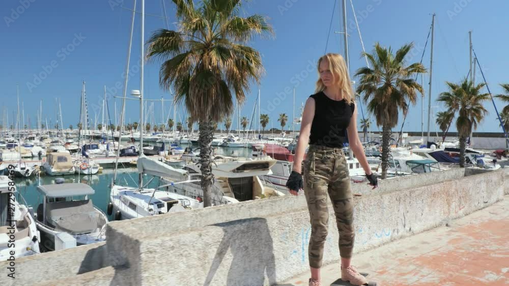 A beautiful blonde girl on skateboard in summer hot day on seafront A beautiful blonde girl on skateboard in summer hot day on seafront