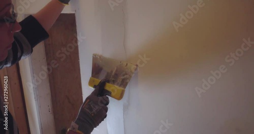women doing home improvment and renovating a wall with new drywalling and spackle photo