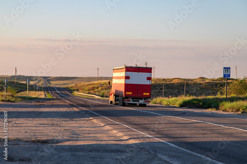 A large red truck transports goods on a long-distance road