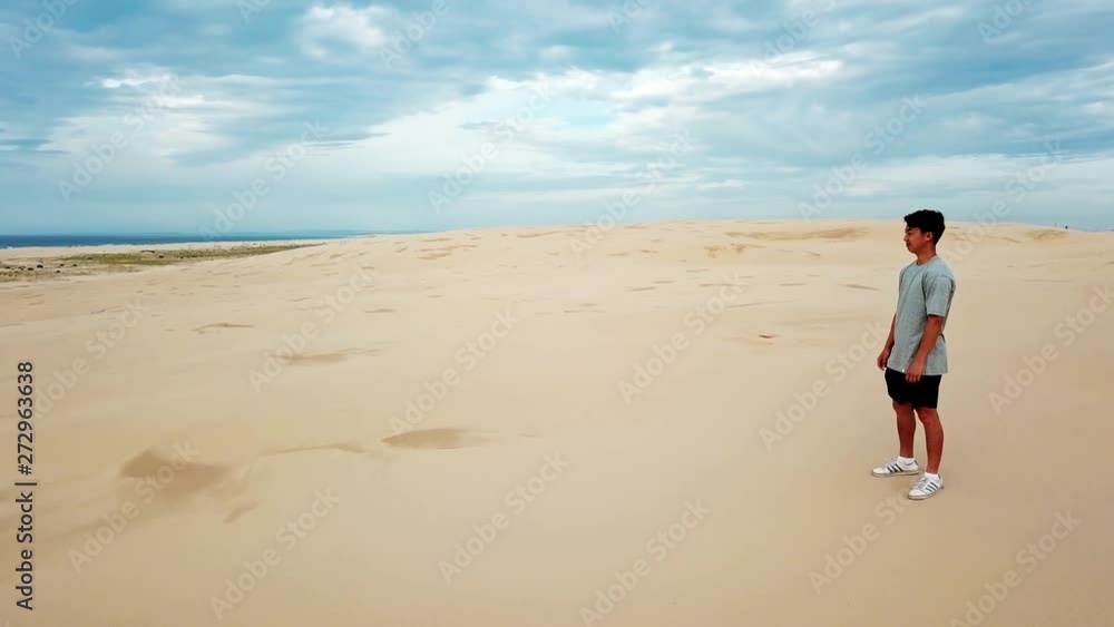 Drone Aerial of Lonely Man Standing At Top Of Dune in Desert Beach With Beautiful Skyline and Looking At Sea in Distance 4k Drone Aerial of Lonely Man Standing At Top Of Dune in Desert Beach With Beautiful Skyline and Looking At Sea in Distance 4k