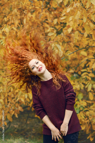 positive beautiful young woman with red long hair on autumn forest background  hair in different directions