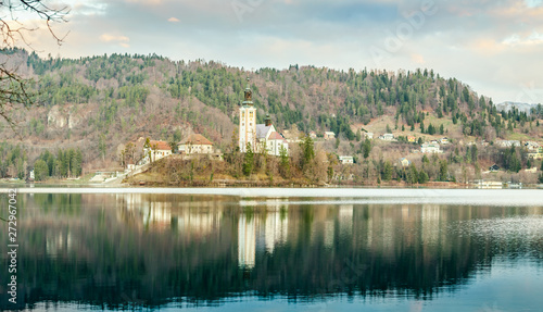 Beautiful view of famous Bled Island (Blejski otok) at scenic Lake Bled with Bled Castle (Blejski grad) and Julian Alps in the background in golden morning light at sunrise in April, 2019. Slovenia. 