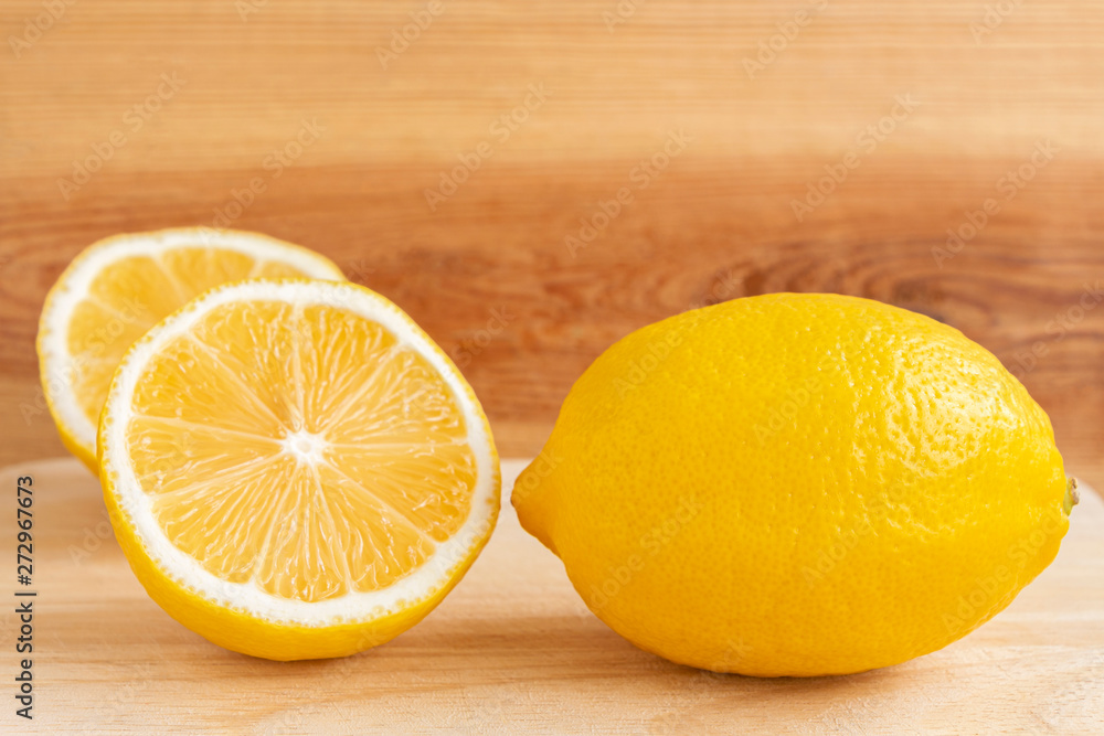 Fresh yellow lemon and half a lemon on a wooden table.