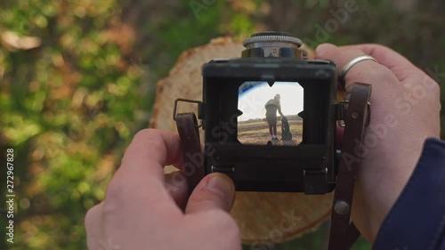 Taking a photograph of a woman standing with a dog with an old film camera. A view through the lens, POV of a photographer. photo