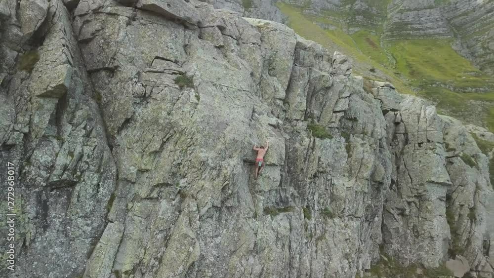 Climber ascends rock why camera moves from left to right revealing mountains in the background Climber ascends rock why camera moves from left to right revealing mountains in the background