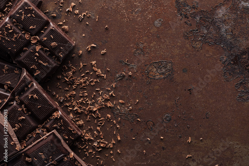 Obraz na plátne Pieces of chocolate bar with chocolate chips on metal background