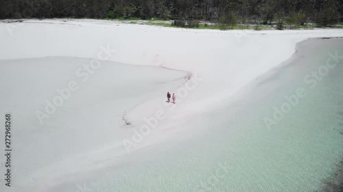 Tourist couple walking on a white sandy beach at Punta Sebaring in Balabac, drone shot in Palawan, Philippines photo