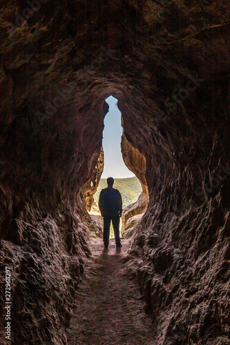 Man silhouette at the end of a small cave