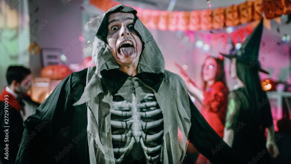 Halloween Costume Party: Sceary Terrifying Screaming Death. In the Background Zombie, Death, Witch, Mummy and She Devil Have Fun in a Monster Party Decorated Room