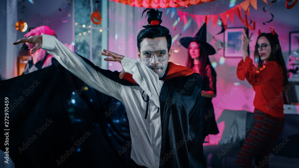 Halloween Monster Costume Party: Vampire Count Dracula wearing His Cape Does Funny Dance, In the Background Beautiful Witch, Gorgeous She Devil and Scary Death Dancing in the Decorated Room