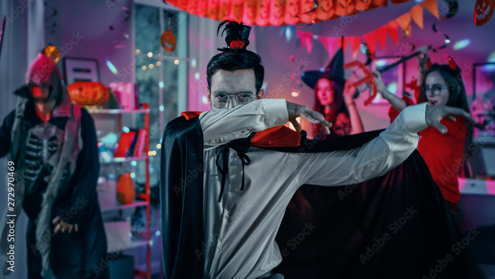 Halloween Costume Party: Count Dracula wearing His Cape Does Doing Vampire Dance, In the Background Beautiful Witch, Gorgeous She Devil and Scary Death and Zombie Dancing in the Decorated Room