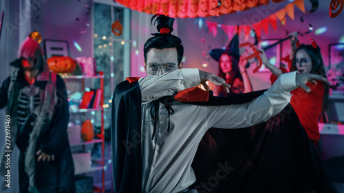 Halloween Costume Party: Count Dracula wearing His Cape Does Doing Vampire Dance, In the Background Beautiful Witch, Gorgeous She Devil and Scary Death and Zombie Dancing in the Decorated Room