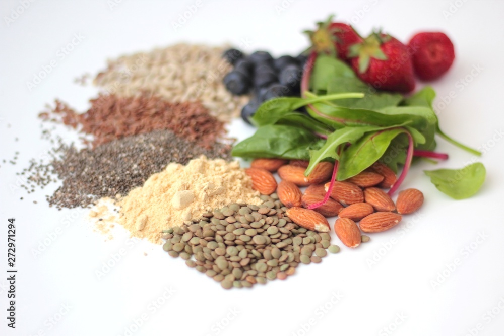 Sample foods from low-GI PCOS (Polycystic Ovary Syndrome) diet. Lentils, almonds, chia seeds, sunflower seeds, flaxseed, maca powder, blueberries, strawberries and dark leafy greens.