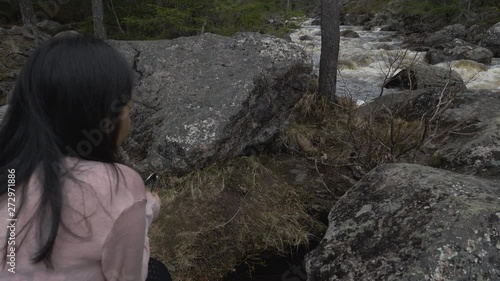 Girl looking at the water on the riverside in the forest photo