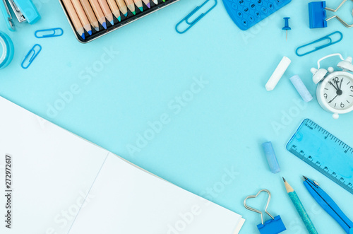 Flat lay mockup stationery, notepad, pens and pencils over classroom blackboard with copy space. Back to school concept. Blue calculator, ruler, compass and stapler on a blue background