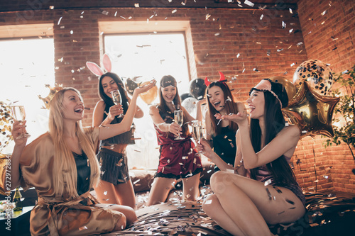 Nice attractive lovely royal funny cheerful group ladies having fun time festive celebratory festal mood glow glossy elements flying in golden decorated loft industrial style interior room house