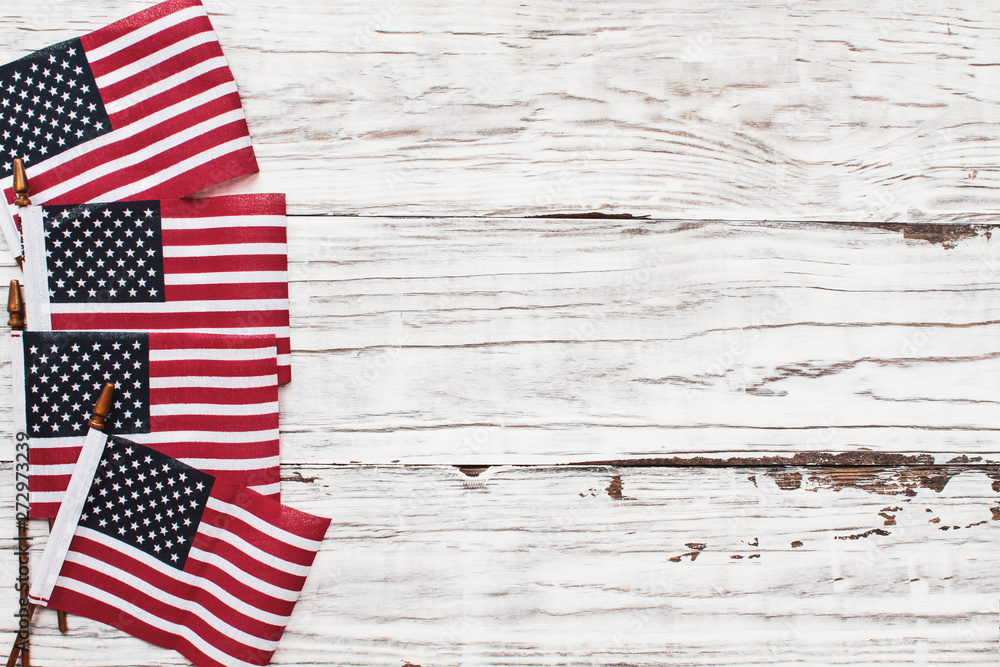 Obraz premium American Flags for the America's 4th of July Celebration over a white rustic background to mark America's Independence Day. Image shot from top view.