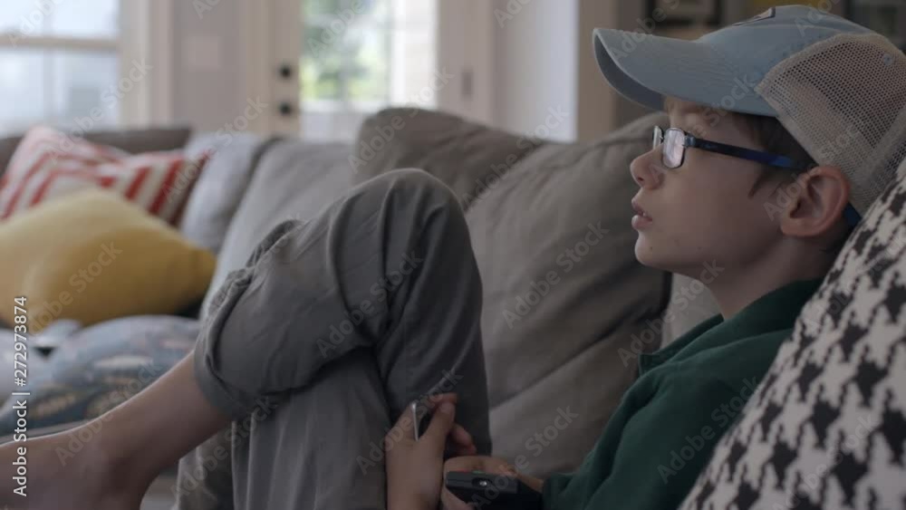 a cute boy with a remote control watches tv a cute boy with a remote control watches tv