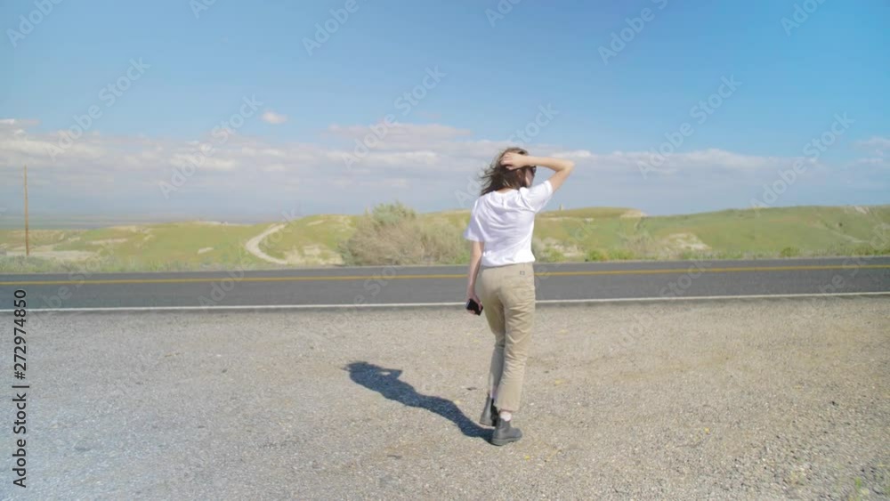 wide shot of girl on the roadside of highway waiting for car wide shot of girl on the roadside of highway waiting for car