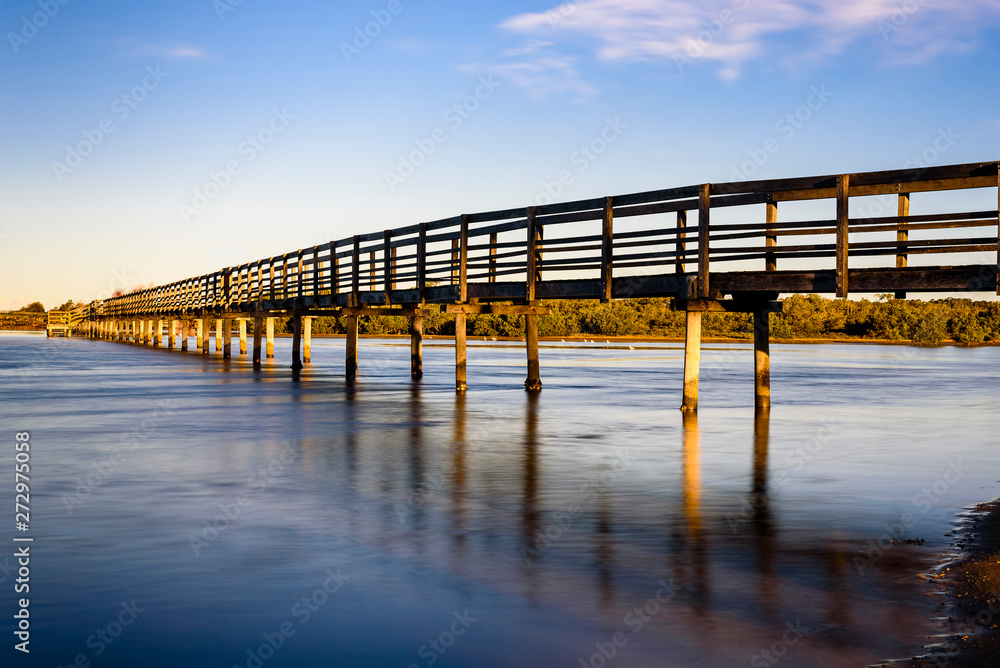 Wooden boardwalk over the sea in Urunga, New South Wales, Australia. Long exposure landscape at sunrise. 