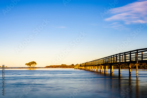 Wooden boardwalk over the sea in Urunga, New South Wales, Australia. Long exposure landscape at sunrise. 