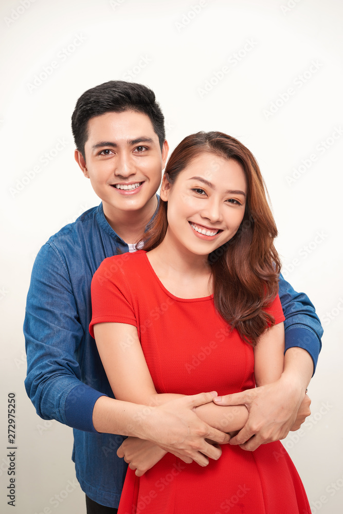 Portrait of a young couple hugging and standing against white background Portrait of a young couple hugging and standing against white background