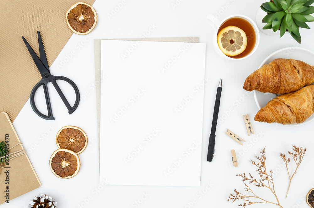 Craftsman workplace mockup with supplies and blank A4 paper list. Tea with lemon, croissants and envelope. Top view, flat lay with copy space Craftsman workplace mockup with supplies and blank A4 paper list. Tea with lemon, croissants and envelope. Top view, flat lay with copy space
