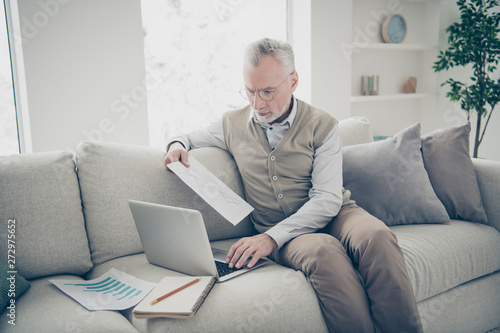 Close up side profile photo amazing he him his aged man hand arm notebook search analyzer check information charts stats wear white shirt waistcoat pants sit cozy divan flat house living room indoors