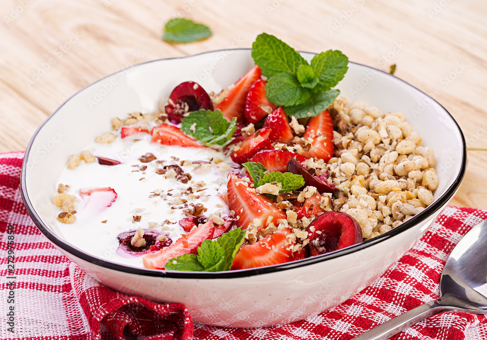 Healthy breakfast - granola, strawberries, cherry, nuts and yogurt in a bowl on a wooden table. Vegetarian concept food. Healthy breakfast - granola, strawberries, cherry, nuts and yogurt in a bowl on a wooden table. Vegetarian concept food.