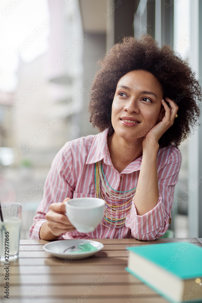 Attractive mixed race woman sitting in cafe and enjoying her coffee. Attractive mixed race woman sitting in cafe and enjoying her coffee.