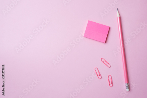Pink Notepad paper clip and pencil on pink background with copy space. Concept school education, office and freelancing.