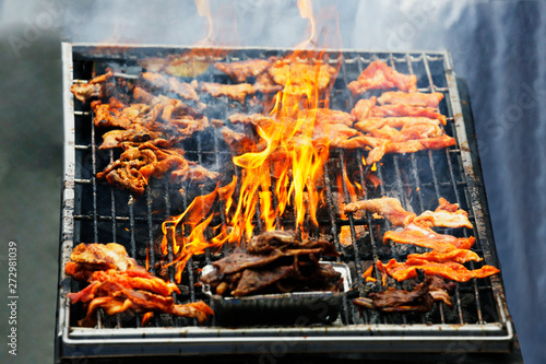 Summer BBQ grilling marinated pork on fire, Korean style..