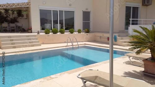 Wallpaper Mural Gimbal Shot of Sun Loungers, Umbrellas & Miniature Palm Trees with Luxury Greek Villa in Background Torontodigital.ca