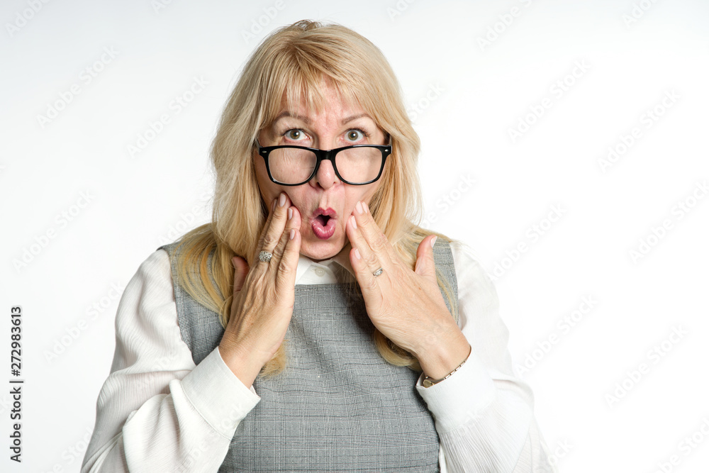 Surprised mature woman in glasses gestures her emotions on a light background. Surprised mature woman in glasses gestures her emotions on a light background.