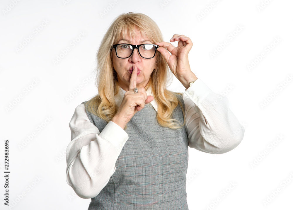 Quiet! Standing woman in glasses shows a gesture of silence on a light background. Keep your finger near the lips.