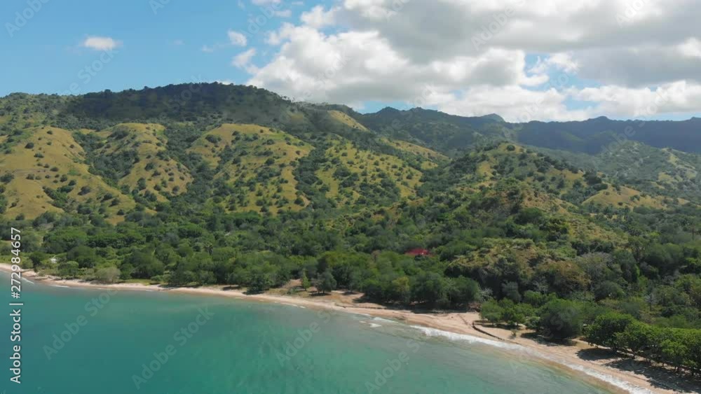 Beautiful aerial view of the Komodo Island landscape flying over the sea. A long wooden pier juts out into the turquoise sea. White sand beach rings the lush green island. Indonesian island paradise. Beautiful aerial view of the Komodo Island landscape flying over the sea. A long wooden pier juts out into the turquoise sea. White sand beach rings the lush green island. Indonesian island paradise.